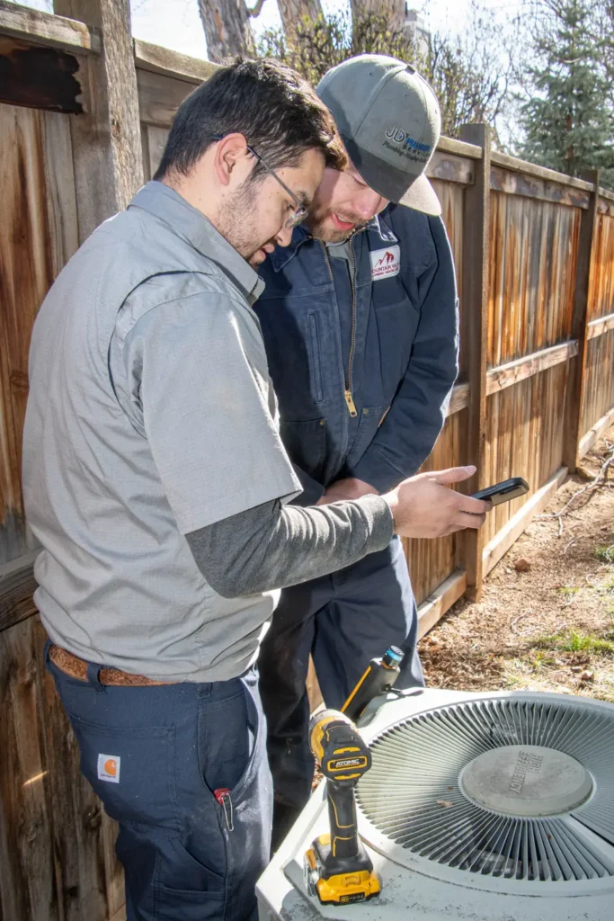 Technicians inspecting an air conditioning unit outdoors