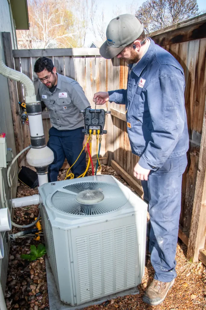 Technicians repairing home air conditioning unit outdoors