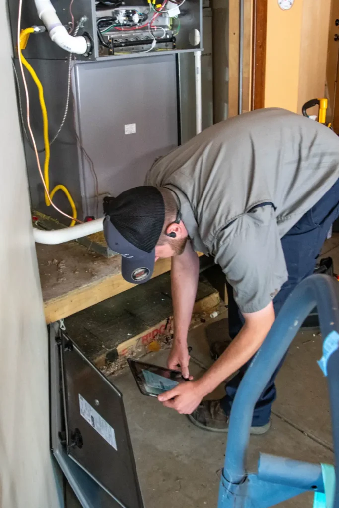 Technician inspecting a home heating furnace for maintenance