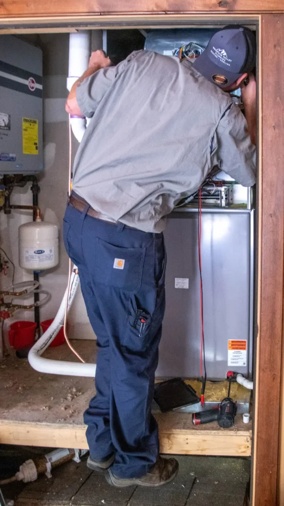 Technician servicing a furnace in a utility room