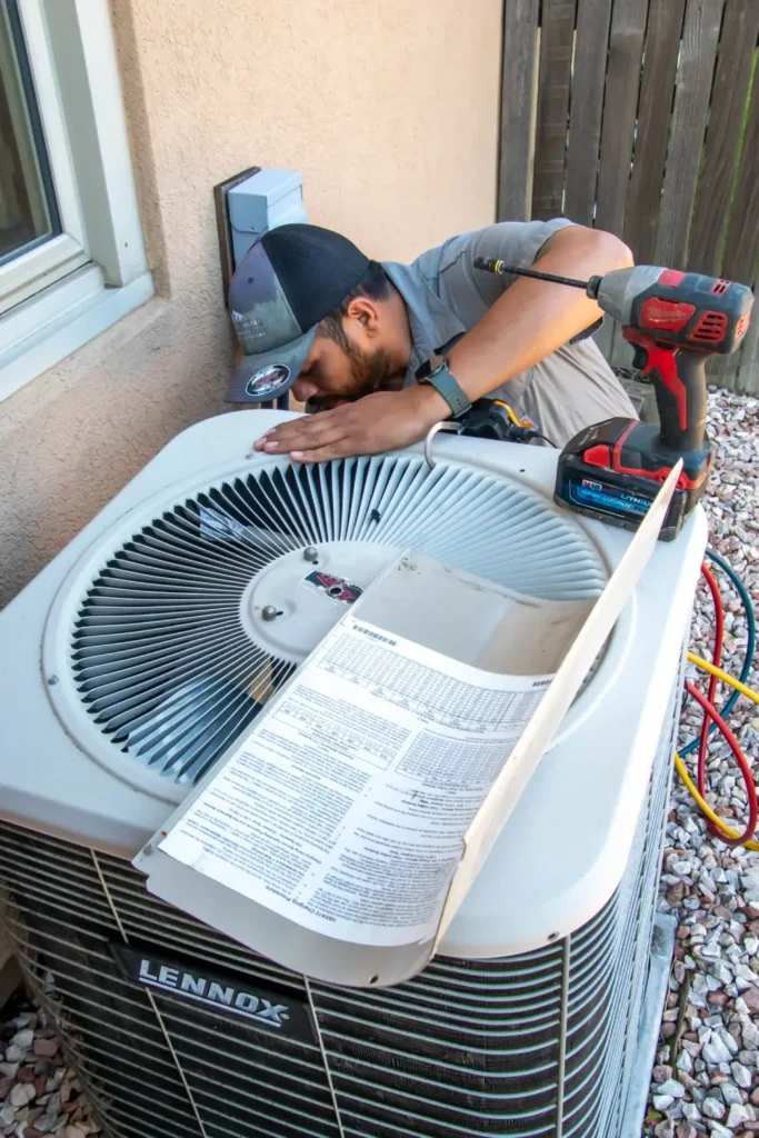Technician inspecting an outdoor air conditioning unit repair