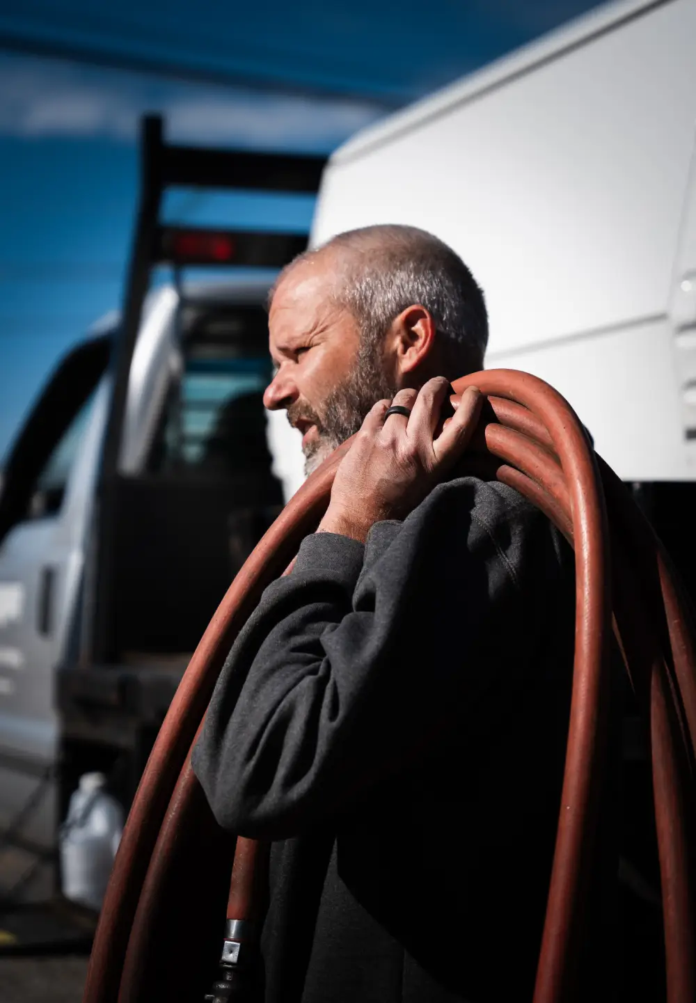 Man carrying hose near truck on a sunny day