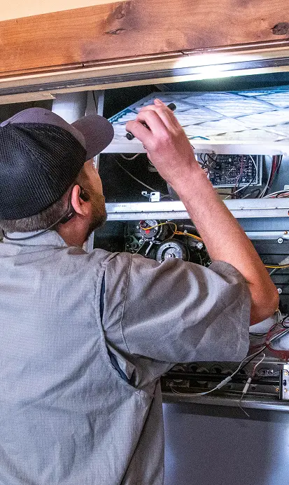 HVAC technician inspecting and repairing internal components of a furnace or air handler unit.