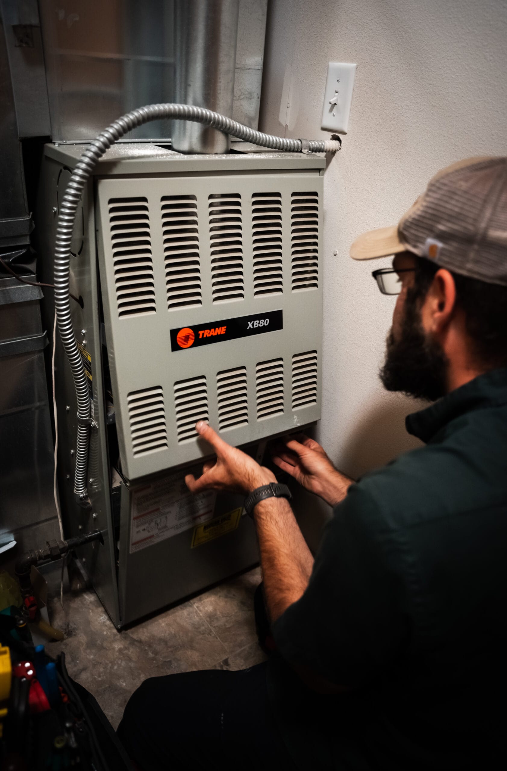 HVAC technician inspecting a Trane furnace panel during residential heating system maintenance and repair service in a utility room