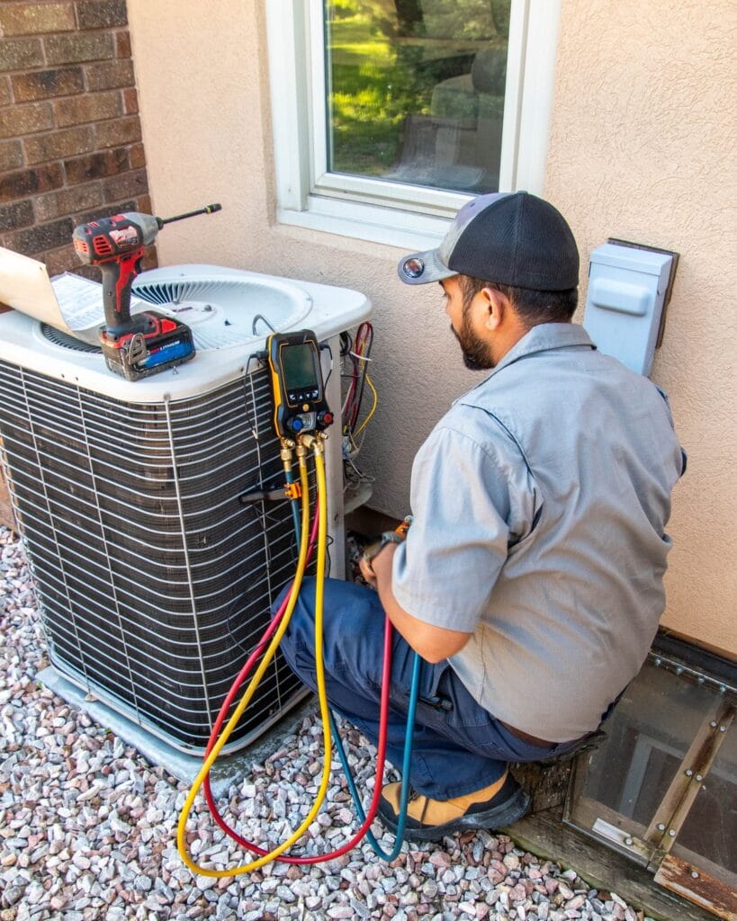 Mountain Valley HVAC technician checking refrigerant pressures on an outdoor air conditioning unit at a Johnstown, CO home