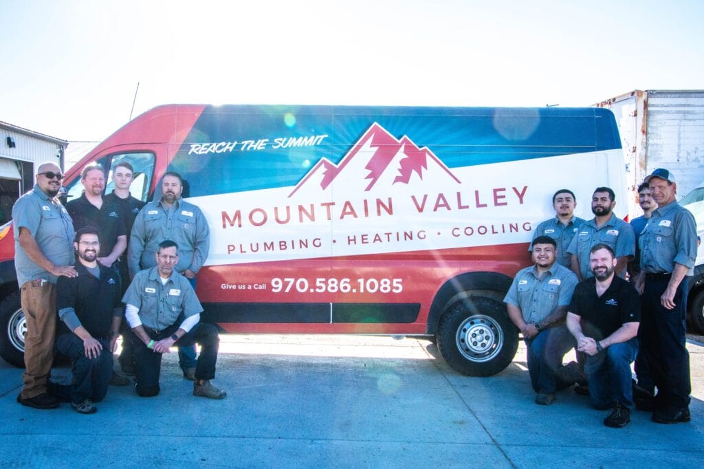 Mountain Valley Plumbing, Heating and Cooling technicians standing in front of a branded service van serving Johnstown, CO